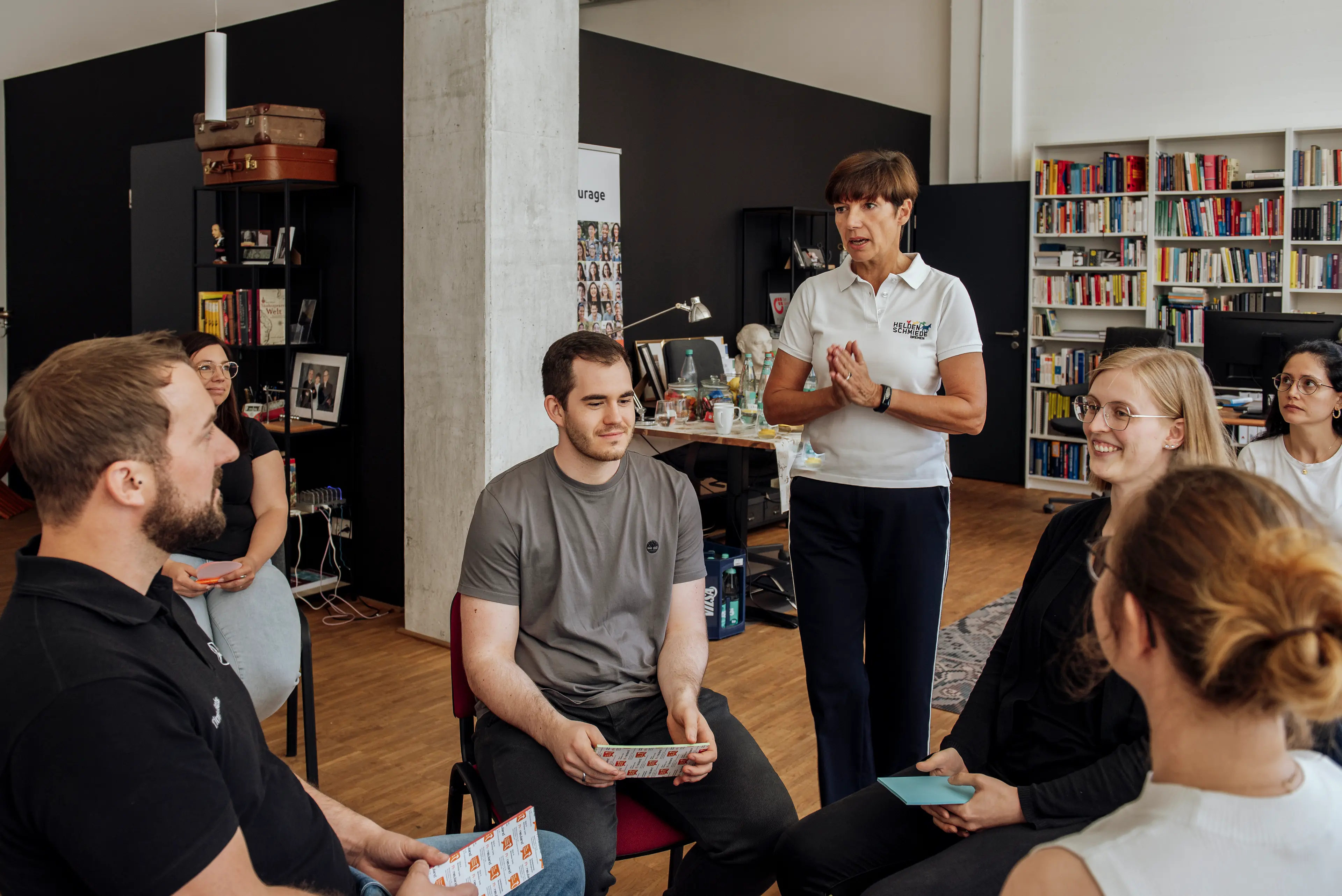 Raphaela zwischen sitzenden Seminarteilnehmend stehend.